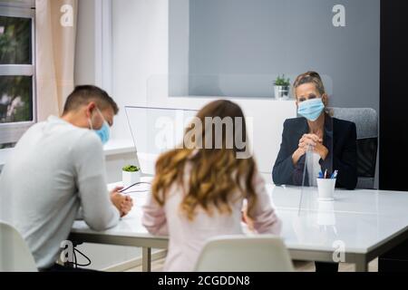 Young Family Couple Meeting Consultant Or Lawyer With Face Masks Stock Photo
