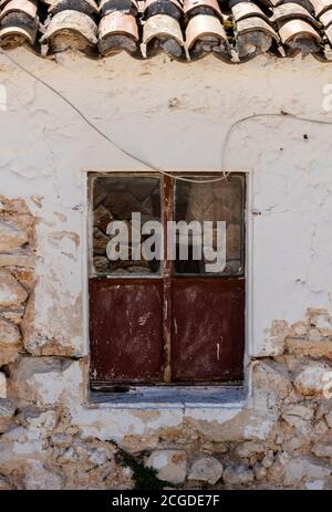 an old broken window on a delapitated wall on a building on the greek island of zante in zakynthos, greece Stock Photo