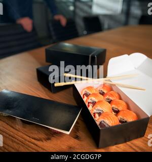 Sushi roll delivery box on workspace with chopsticks. Office lunch Stock Photo