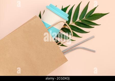Paper bag with bamboo cup and reusable drinking straws on pink background. Mockup, top view. Zero waste concept Stock Photo