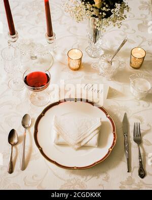 Wedding place setting on textured tablecloth in warm light with name Stock Photo