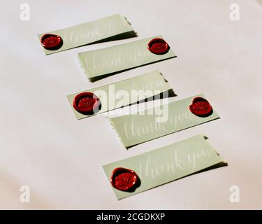 Green "Thank You" tags with red wax seal in warm afternoon sunlight Stock Photo