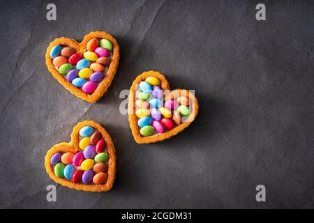 Candy Buttons on Heart shaped cake on black slate Background - Birthday concept Stock Photo