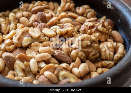 Mix of seeds, walnut, peanuts and almonds in a bowl on wooden table. Stock Photo