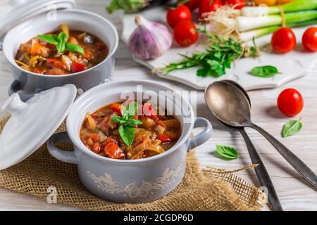 Delicious Italian vegetable minestrone soup served in small pots with ingredients Stock Photo