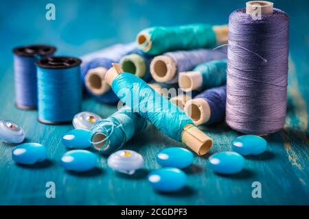 Sewing threads and sewing buttons, spools in blue tone. Needlework and tailoring concept Stock Photo