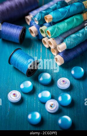 Sewing threads and sewing buttons, spools in blue tone. Needlework and tailoring concept Stock Photo