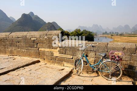 Scenery along the Yulong River near Yangshuo, Guilin in Guangxi Province, China. A bicycle on a stone bridge crossing the Yulong River Stock Photo