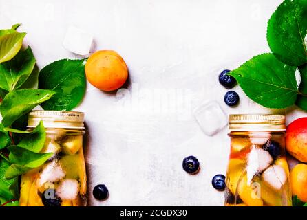 Two bottles with fruit tea with apricot, blueberry and ice, food background, top view Stock Photo