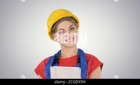 Young construction worker with tablet computer presenting something on gradient background. Stock Photo