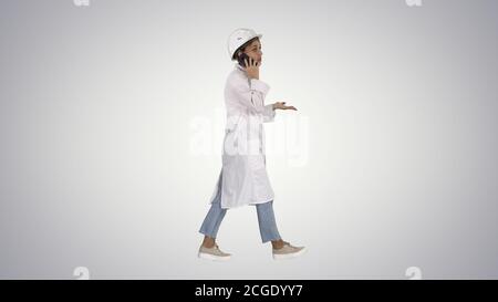 Female scientist making a call walking on gradient background. Stock Photo
