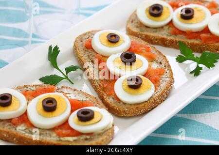 Swedish Open Sandwich with sliced boiled egg, black olives and dill on top of seasoned cod roe rye bread. Stock Photo
