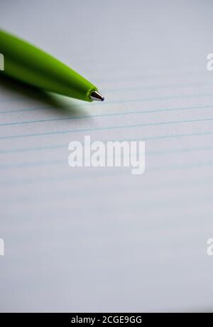 Green ballpoint pen on a lined notebook Stock Photo