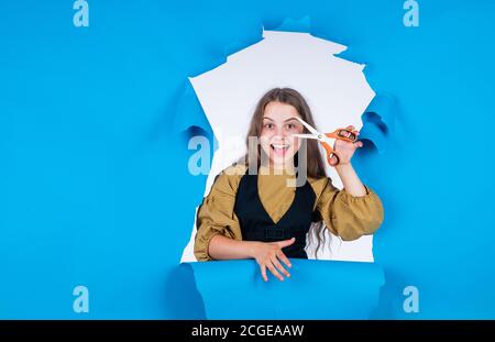 kid is trimmed in the hairdressers. child with scissors wants to cut hair. girl in hairdressing salon. teenager cutting hair. Cute girl cutting hair to herself with scissors. Stock Photo