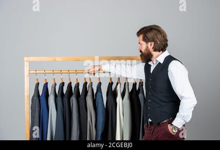 Man picking suit from personal wardrobe, tailored blazer concept. Stock Photo