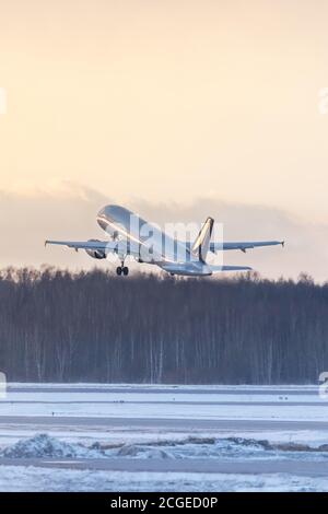Airplane taking off during a sunset in winter time. Aviation concept Stock Photo