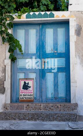 blue door in the old town with the sign 'beware of the dog' in greek on the door Stock Photo