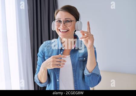 Portrait of mature positive talking woman in headphones Stock Photo