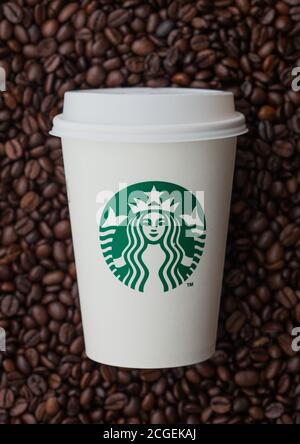 LONDON, UK - SEPTEMBER 09, 2020: Paper cup for takeaway of Starbucks coffee on top of fresh raw coffee beans. Stock Photo