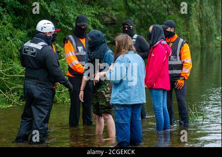 Denham, Buckinghamshire, UK. 8th September, 2020. A young female tree protector scaled a tree this morning earmarked to be cut down by HS2. Other activists stand under the tree in the River Colne to support her and are surrounded by National Eviction Team Enforcement Agents and HS2 security guards. The controversial HS2 High Speed Rail link is set to damage or destroy 108 ancient woodlands. Credit: Maureen McLean/Alamy Stock Photo