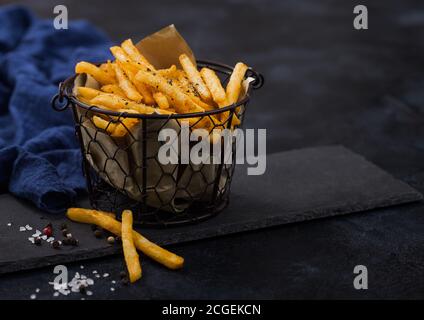 French fries chips in snack bucket on black stone board with blue towel on dark background. Stock Photo