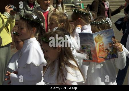 Poland; Girls in white communion dresses and a wreath on their heads. The girl is engrossed, absorbed in reading. Mädchen in weißen Kommunionkleidern. Stock Photo