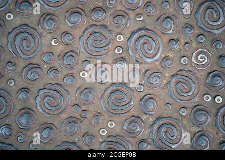 Metal surface with embossed curls in relief. Metal sheet with curls background. Stock Photo