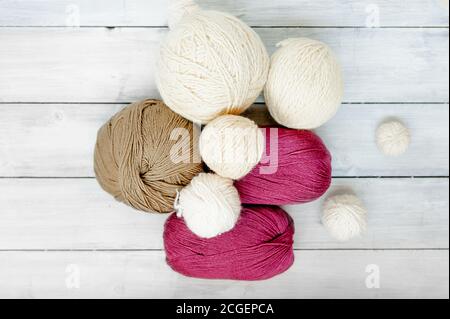 multicolored wool balls of knitting threads on a light wooden table, top view Stock Photo