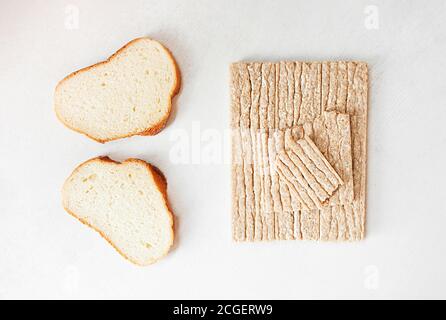 Different types of bread, white yeast bread and healthy crispbread on a white cement table, top view Stock Photo