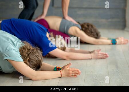 Group of caucasian adult women practicing yoga under male instructors guidance in studio. Stock Photo