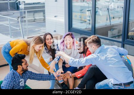 Excited creative group of multiethnic people co-workers giving high-five in outdoor meeting room at creative office Stock Photo