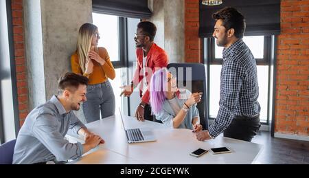 Indoor shot of group of multiracial students having meeting at loft studio space background, using laptop and smartphone internet sources trying to wr Stock Photo