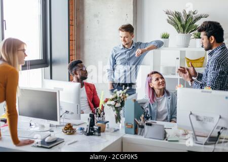 Young African constructor sharing new ideas about project to his partners in office working room. Multiethnic coworkers discussing over new business p Stock Photo