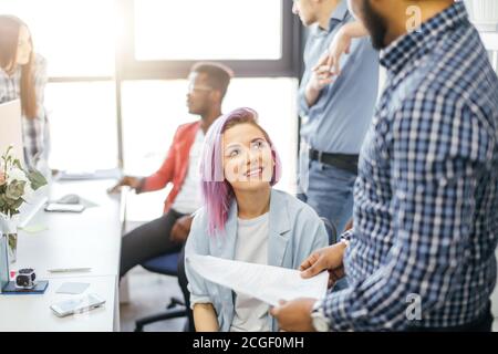 Female designer sharing new ideas about new project to her partners in office working room. Multiethnic coworkers discussing over new business project Stock Photo