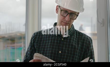 Builder engineer wear security helmet look at blueprint paper co Stock Photo