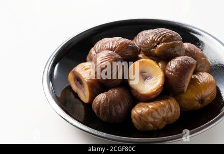 Peeled sweet chestnuts in a plate on a white background Stock Photo
