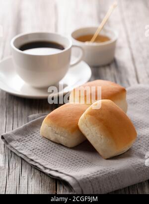 Dinner rolls, coffee and honey set against an old wooden backdrop. Breakfast Image. Stock Photo