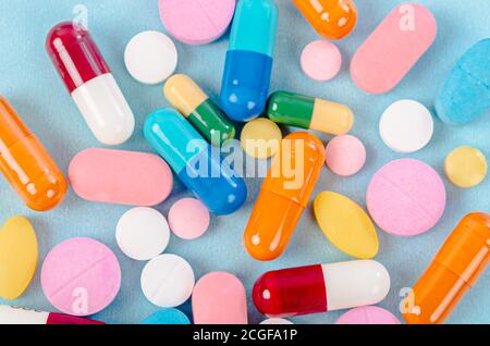 Colored pills, tablets and capsules on a blue background Stock Photo