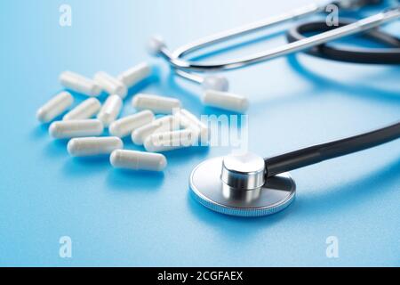A stethoscope and pills placed on a blue background. Medical Image Stock Photo