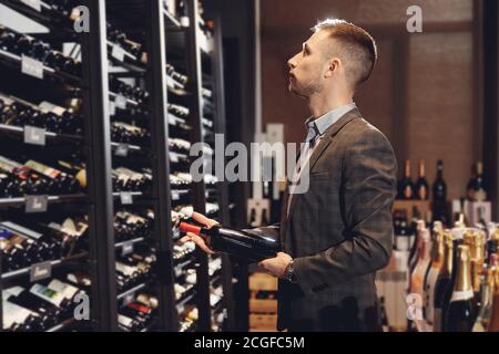 Sommelier takes bottle of red wine from counter of restaurant drinks store Stock Photo