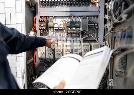 Worker engineer checks electrician measurements with tester multimeter for industrial production Stock Photo