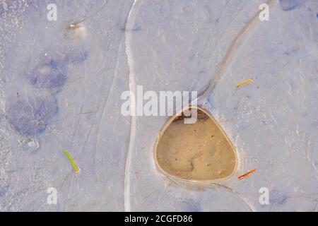 Thin ice with a hole on a beach Stock Photo