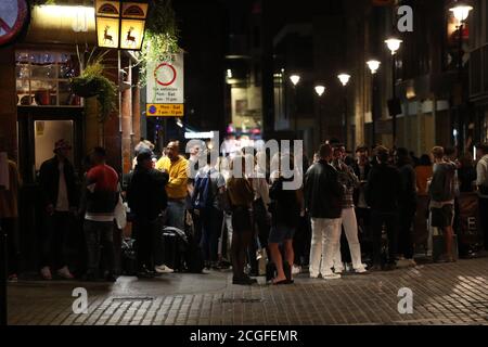 Young people outside the Blue Posts pub in Berwick Street, Soho, London. People in England will be banned from meeting in groups of more than six from Monday as ministers try to tackle the rising number of coronavirus cases across the UK. Stock Photo