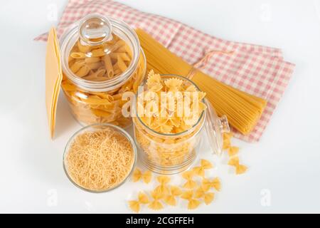Different types of Italian uncooked pasta on white background. Glass jars with different types of pasta, spaghetti and noodles. Stock Photo