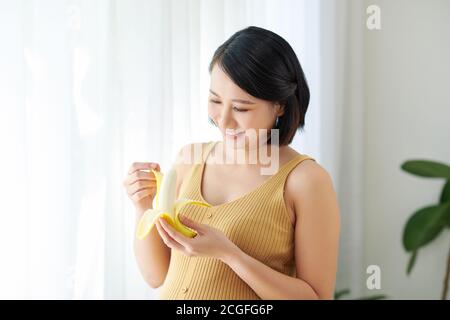 pregnant woman on kitchen making healthy fruit juice and eating banana Stock Photo