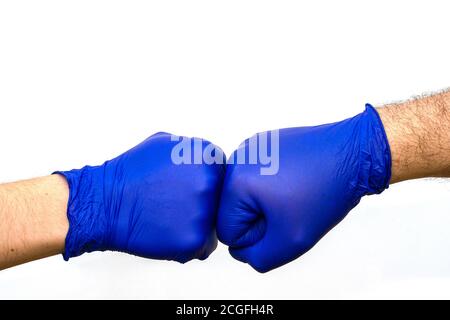 hands in blue protective surgical gloves greet each other with their fists Stock Photo