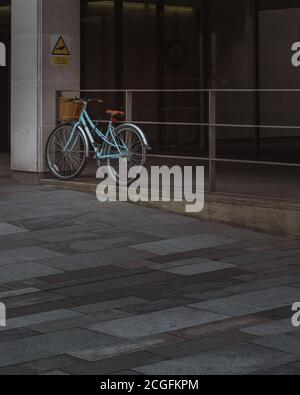 A lonely blue bike leaning against railings outside Manchester Crown Court Stock Photo