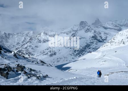 Zermatt, Switzerland - Feb 18 2020: A couple walking in a winter mountain landscape. Stock Photo