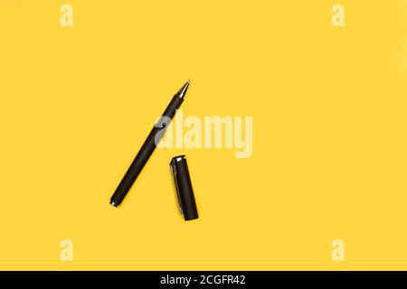 An open black ballpoint pen on a yellow background with copy space Stock Photo