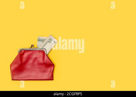 Old red coin purse with a five dollar note on a yellow background Stock Photo